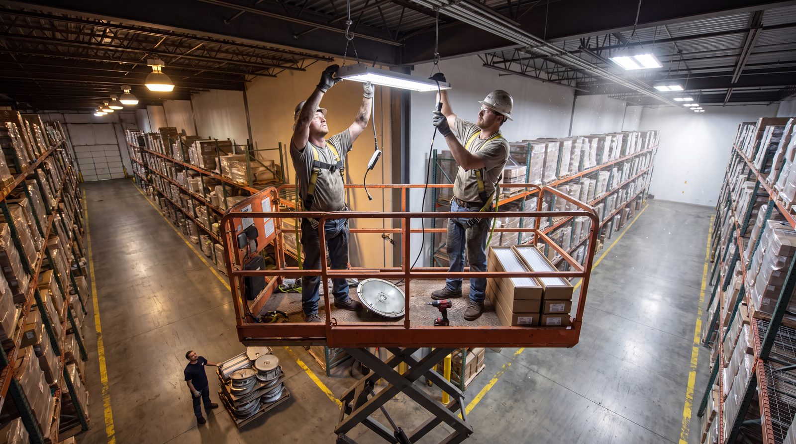 Electricians replacing high-bay LED fixtures in a warehouse